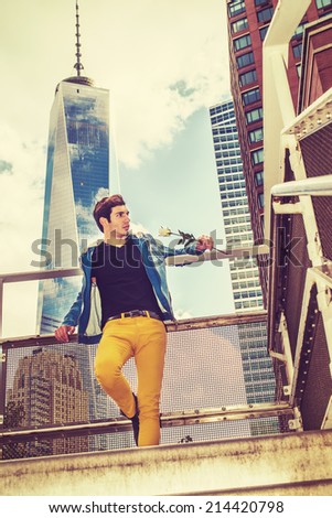 Man Waiting for You. Dressing in blue jacket with hood, black under wear, yellow pants, holding a white rose, a young handsome guy is standing in the front of high tower building, looking forward.