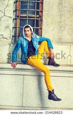Man Waiting for You. Dressing in a blue jacket, hood covering head, black underwear, yellow pants, leather boot shoes, a young handsome guy is sitting by a window, looking around, Street Fashion.