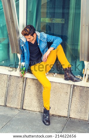 Man Missing You. Dressing in a blue jacket with hood, yellow pants, leather boot shoes, a young handsome guy is sitting by a metal structure, holding a white rose, looking down, sad, thinking.