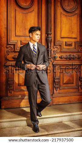 Business Man. Dressing in a black suit, patterned necktie, vest, leather shoes, a young handsome college student is walking down stairs from an old fashion style office door.
