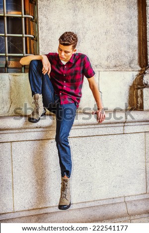 Man Thinking Outside. Dressing in a short sleeve, black, red patterned shirt, jeans, boot shoes, a young handsome guy is sitting by a window, lowering head, looking down at his foot, sad, thinking