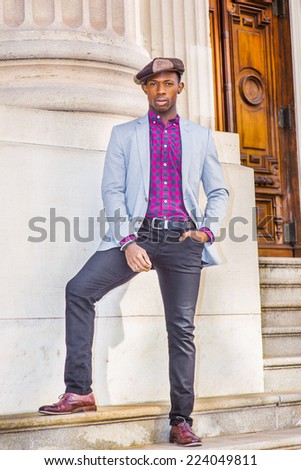 Man Urban Fashion. Wearing fashionable Newsboy cap, dressing in light gray blazer, patterned pink, black under shirt, black pants, brown leather shoes, a young guy confidently standing on stairs
