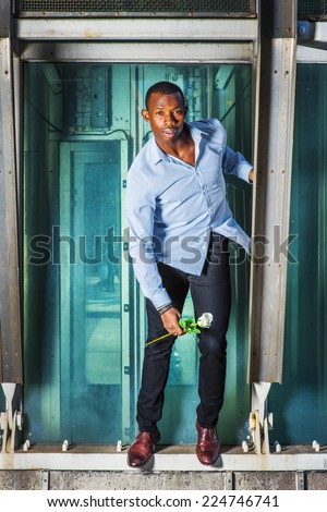 Man waiting for You. Wearing a long sleeve shirt, black pants, brown leather shoes, short haircut, a young black guy is standing on metal structures, holding a white rose, looking forward.