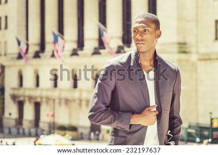 Portrait of Black Teenage Boy. Wearing a white under wear, fashionable jacket, a young black college student is standing in the front of an office building, sad, thinking, lost in thought.