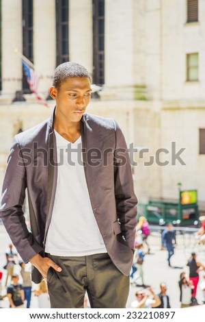 Unhappy Teenage Boy. Wearing a white under wear, fashionable jacket, a young black college student is standing outside office building, looking down, sad, thinking, lost in thought.