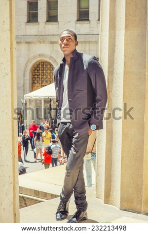 Young black man thinking outside. Wearing a white under wear, fashionable jacket, a young black college student is standing by columns, seriously thinking. Street Fashion.