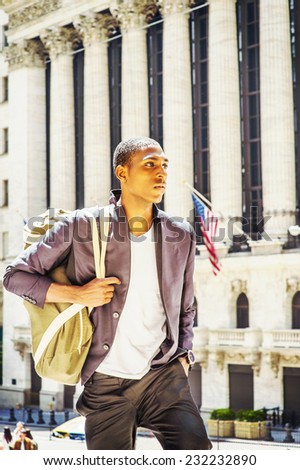 Man Traveling. Carrying a shoulder bag, walking up, a young black college student is standing in the front of an office building, confidently looking forward.