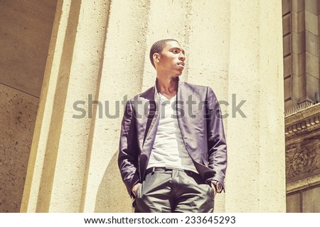 Young black man thinking outside. Wearing a white under wear, fashionable jacket, two hands in pockets, a young black college student is standing under strong sun light, looking forward, thinking.