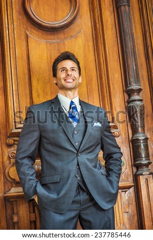 Door to Success. Dressing in a dark blue three piece suit, patterned necktie,  a handsome, sexy, middle age businessman is standing by an old fashion style office door way, confidently looking up.