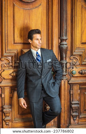 Door to Success. Dressing in a dark blue three piece suit, patterned necktie,  a handsome, sexy, middle age businessman is standing by an old fashion style office door way, thinking, lost in thought.