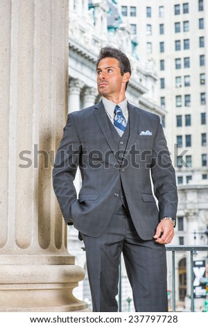 Way to Success. Dressing in dark blue three piece suit, necktie, wearing wristwatch, a handsome, sexy, middle age businessman is standing in the front of office building, confidently looking up.