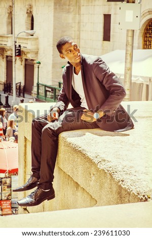 Young man thinking on street. A young black college student is sitting outside, arched the back, turning back, looking up, under strong sunshine, thinking.