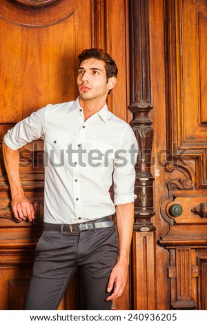 The Door to Success. Wearing a white shirt, black pants, a young college student is standing by an old fashion style office door, looking up, seriously into deeply thinking. Portrait of Business Man
