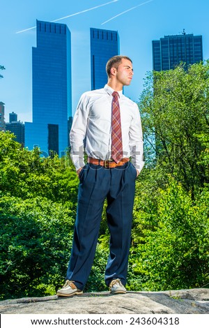 Standing Up, Looking Far. Wearing a white long sleeve shirt, black pants, a pattern tie, short haircut, young professional guy standing in the front of business district, confidently looking forward.