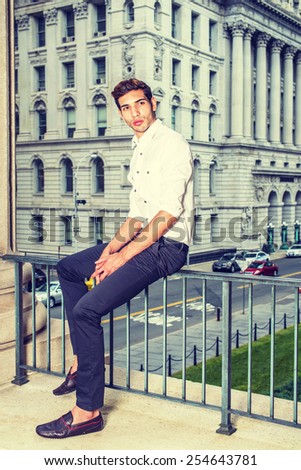 Businessman. Wearing a white shirt, black pants, leather shoes, a young college student is sitting on a railing in a business district, relaxing, thinking. Man Casual Fashion. Instagram filtered look.