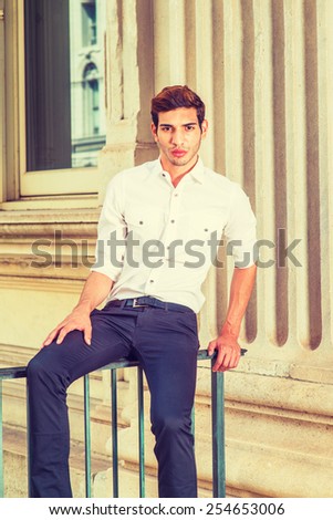 Young Businessman. Wearing white shirt, sleeves rolling over, black pants, a young college student sitting on a railing outside office, relaxing, thinking. Man Casual Fashion. Instagram filtered look.