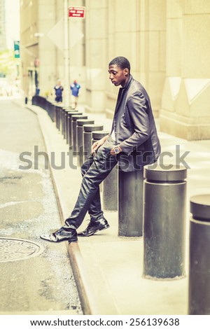 City Boy. Young black college student sitting on street, hunchbacked, sad, tired, looking down, lost in thought. Concept of teenagers questioning life, career, self esteem. Retro filtered look.