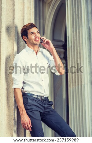 Businessman Calling Outside. Wearing white shirt, black pants, a young college student talking on mobile phone outside an office building. Concept of technology in daily life. Instagram filtered look.