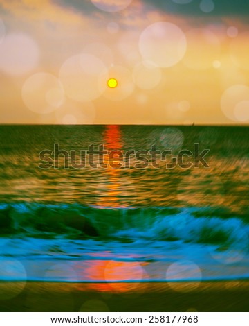 Blur background of sunrise over beach, sun, horizon and running waves. Radial blur effect around sun, bokeh and color filtered look representing to moody, peaceful, romantic environment or atmosphere.