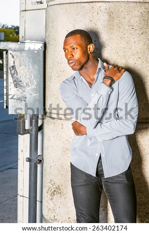 Man Waiting for You. Wearing a long sleeve shirt, bracelets, a young black guy standing against column with metal box and pipe line, a hand touching shoulder and an arm embracing waist, relaxing.