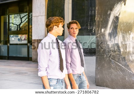 Man looking at Mirror. Young blonde, handsome guy, wearing long sleeve, pink shirt, necktie, jeans, walking by a metal mirror wall, looking at the reflection. Instagram filtered effect.