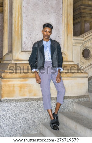 Teenage Fashion. A young, 18 years old student, wearing black fashionable leather, wool mixed jacket, striped pants, blue dyed white shirt, leather shoes, standing outside, relaxing, thinking.
