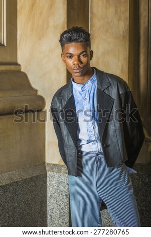 Teenage Fashion. A young,18 years old student, wearing black fashionable leather, wool mixed jacket, blue dyed white shirt, striped pants, standing at the corner, hands in back, waiting for you.