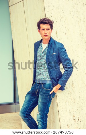 Man Urban Casual Fashion. Wearing blue blazer, patterned under shirt, jeans, hands in back pockets, a young European college student standing against column, waiting for you. Instagram filtered effect