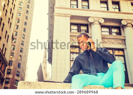 African American businessman with scar on his head, working on laptop computer, talking on phone in New York, Concept of facing reality, up and down, self assured, self esteem, confidence and success.