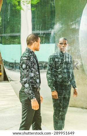 Man looking at mirror. Tough African American businessman, walking by metal mirror wall, looking at the reflection. Concept of self assured, self esteem, self checking strategies. Instagram effect.