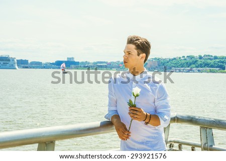 Man Missing You. Wearing white shirt, holding white rose, a young guy standing by Hudson River in New York, opposite New Jersey, waiting for you. Boat, ship on background. Instagram effect. Copy Space