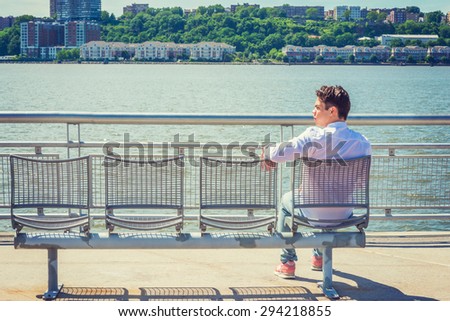 Empty Chairs for You. lonely man seeking friendship. Wearing white shirt, jeans, sneakers, a young lonely guy sitting by Hudson River in New York, facing New Jersey, waiting for you. Copy Space.