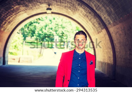 Businessman traveling in New York. Dressing in red blazer, pocket square, blue collarless shirt, a young guy walking through under bridge, confidently looking forward. Instagram effect. Copy space.