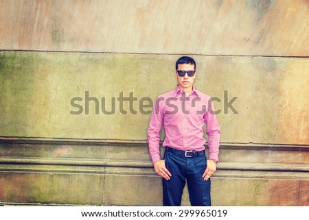 Man casual fashion. Wearing red patterned, long sleeve shirt, black pants, sunglasses, a young guy standing against vintage style wall, confidently looking forward. Copy space. Instagram effect.