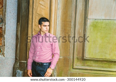 Portrait of College Student. Man casual fashion. Wearing red patterned, long sleeve shirt, black pants, a young guy standing against vintage style wall, confidently looking forward. Copy space.