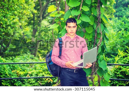 Researching in Raining Day, foggy, drizzling, grainy feel on background. Carrying shoulder bag, holding laptop computer, a college student standing in forest, studying, researching. Instagram effect