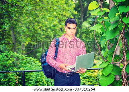 Researching in Raining Day, foggy, drizzling, grainy feel on background. Carrying shoulder bag, holding laptop computer, a college student standing in forest, studying, researching. Instagram effect.