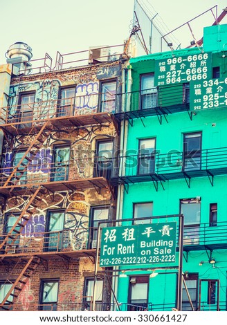 NEW YORK - OCTOBER 21, 2015: Two buildings, one with graffiti, other with signs, Job Agency, For Rent, Building on Sale, located in Chinatown, Manhattan. Chinese American people housing in New York.