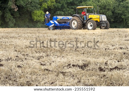 Parana, Brazil, December 08, 2009: Farmer in tractor sowing crops at field with seed scattering agricultural machine