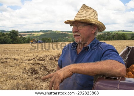 Parana, Brazil, December 08, 2009: Farmer and tractor sowing crops at field with seed scattering agricultural machine