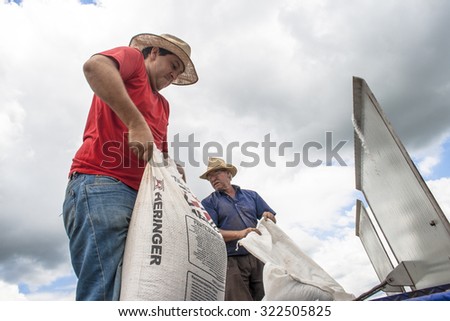 Parana, Brazil, December 8, 2009: two farmers loads of soybeans seeds a planter machine