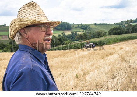 Parana, Brazil, December 08, 2009: Farmer in tractor sowing crops at field with seed scattering agricultural machine and another farmer checks planting in field.