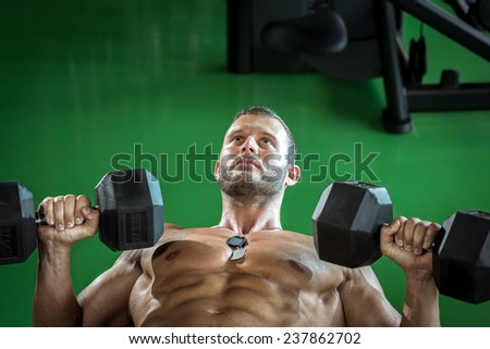 Young bodybuilder doing biceps curls and press while lying down.