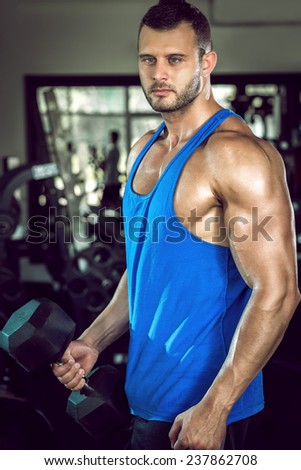 Young adult man doing bicep curls in gym