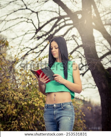 Young adult girl reading a book in park outdoor