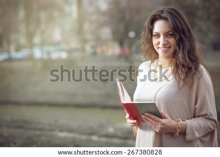 Young adult girl reading a book in park wearing nice blouse