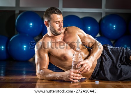 Young adult bodybuilder taking relax lying on gym floor.