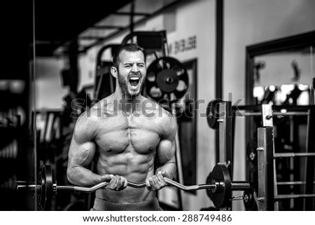 Young adult bodybuilder doing weight lifting in gym while screaming