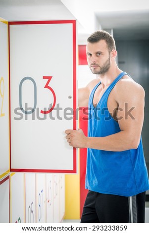 Young adult man opens locker door in gym with number three and standing there.