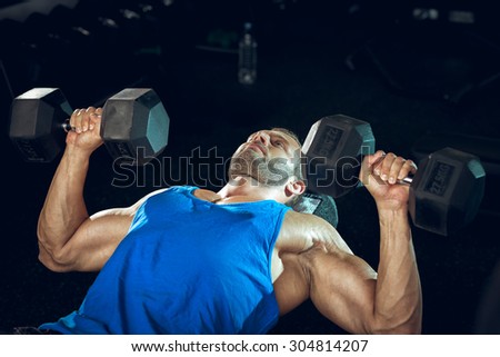 Young adult male bodybuilder doing bicep curls while lying down